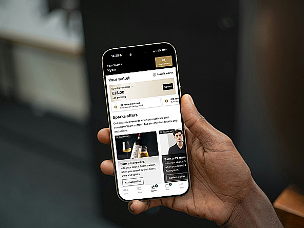Hand holding smartphone, with screen displaying digital interface of M&S customer rewards programme